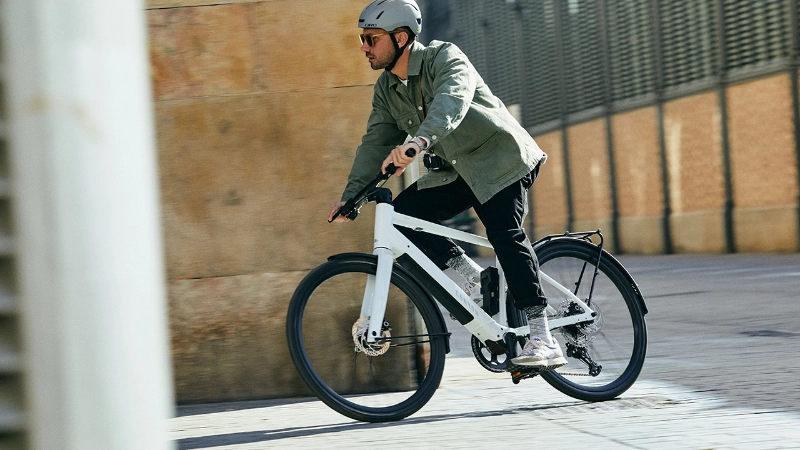 Radfährer fährt mit einem weißen Canyon um eine Straßenecke