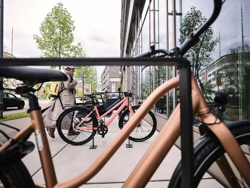 Eine Frau kommt mit ihrem Fahrrad am Büro an Eine Frau kommt mit ihrem Fahrrad am Büro an